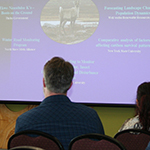 Workshop attendees looking at the slideshow being presented onstage.