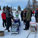 ARENA participants standing outside in the snow in front of a dog sled.