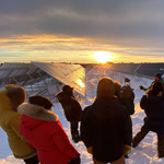 Les participants sont debout dans la neige, faisant face à des panneaux solaires.