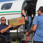 Trois personnes chargent un avion avec des boîtes de nourriture.