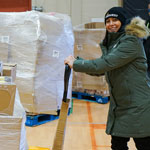 Une travailleuse de Harvest Manitoba poussant une palette contenant des boîtes de nourriture.