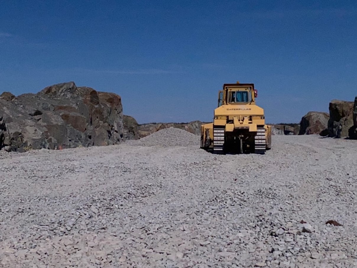 A bulldozer evens out aggregate material in front of a rocky outcrop on the upper pad of the AR1 pad.